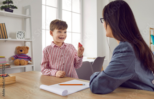 Female speech therapist with a little boy patient practicing private development lessons. Young woman teacher with a child training articulation and pronunciation. Speech practice and therapy concept