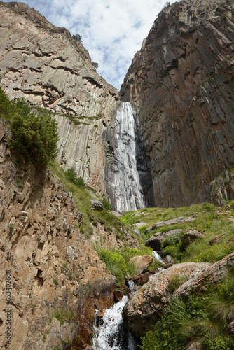 Large waterfall in middle of rocks, high mountains and water flowing among stones