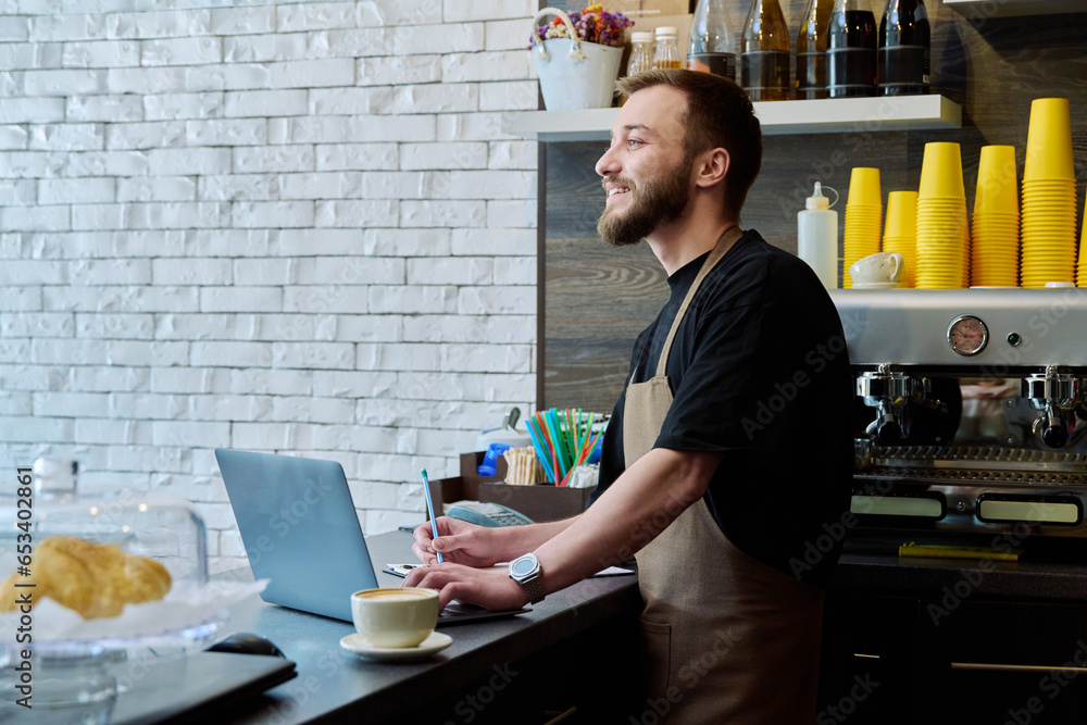 Owner coffee shop worker young male with laptop on the counter Owner coffee shop worker young male with laptop on the counter