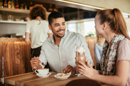 Young interracial couple having coffee together while on a date in a cafe or bar