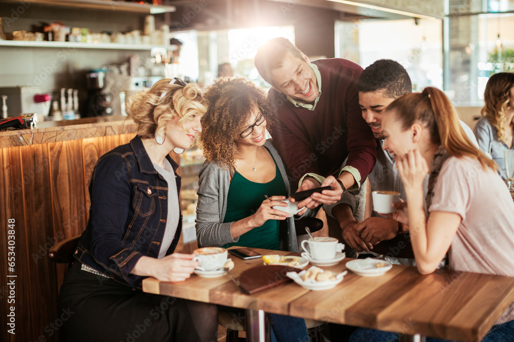Group of young and diverse friends using a smartphone while having coffee together in a cafe or bar