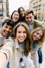 Vertical shot of young millennial people taking selfie with phone at city street. Youth community and friendship concept.