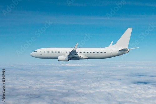 White passenger airliner flying in the air above the clouds