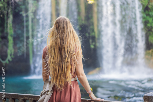 Beautiful woman with long hair on the background of Duden waterfall in Antalya. Famous places of Turkey. Apper Duden Falls