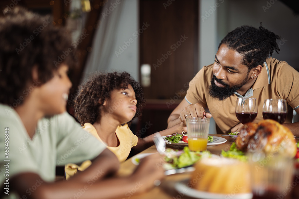 Single African american father talking with his daughter during lunch in dining room