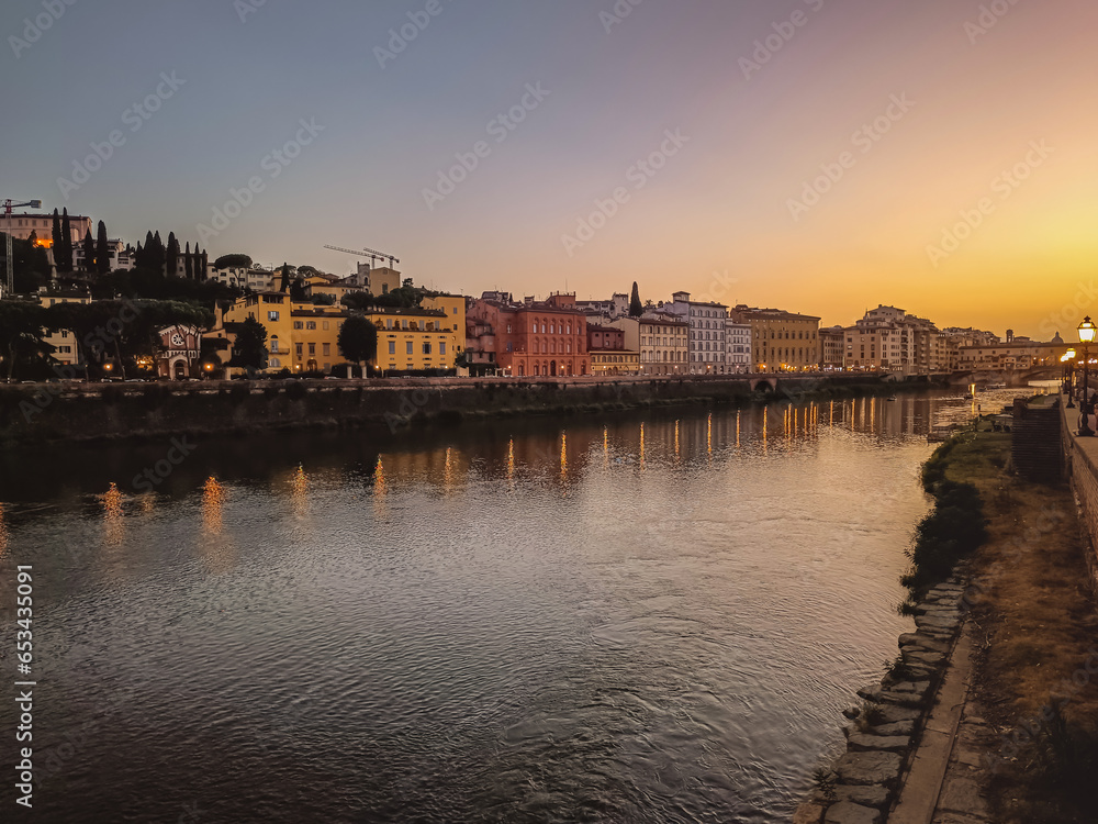 Bank of the River Arno at dusk with street lamp lights reflected in the water, Florence ITALY