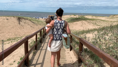 Woman walking towards beach shore holding baby © Marco