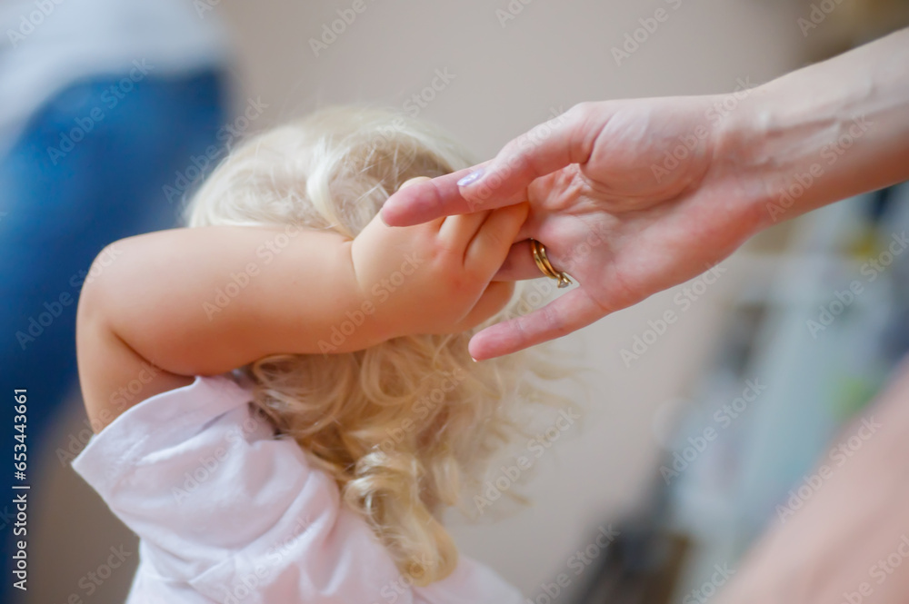 Naklejka premium Little girl entails mom hand
