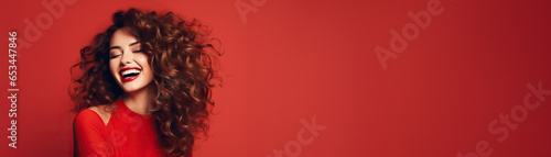 Smiling woman hairstyle wavy curls with red lips on red studio background