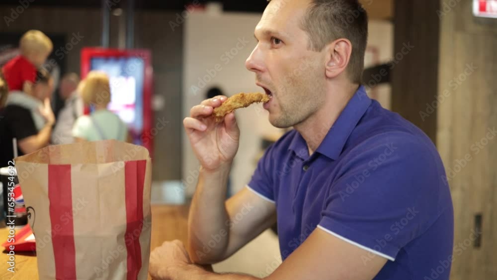 Attractive young man eating chicken wings, high calorie food, health