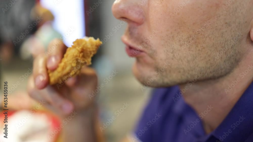 Attractive young man eating chicken wings, high calorie food, health