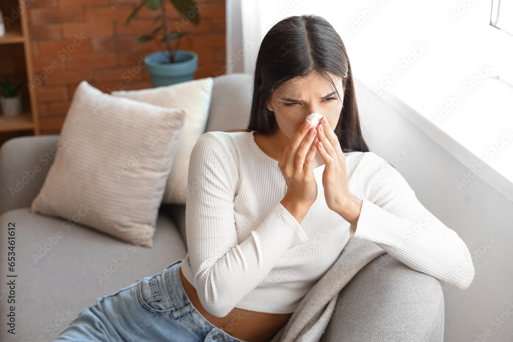 Allergic young woman sneezing with tissue at home Allergic young woman sneezing with tissue at home