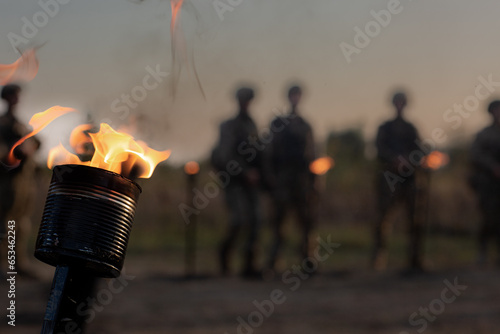 A burning homemade torch against the background of military people in a haze
