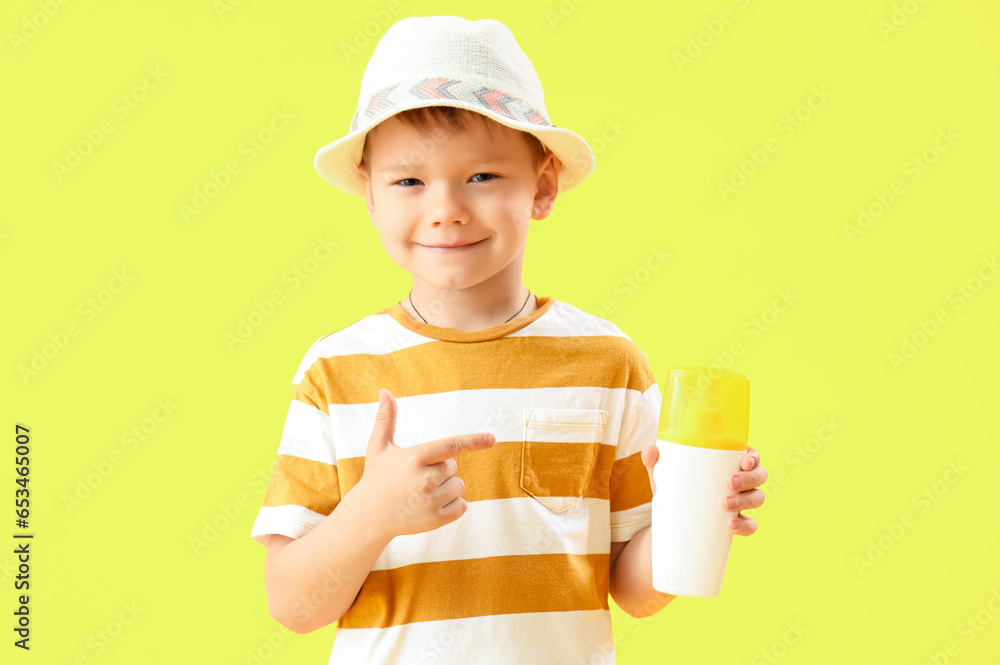 Little boy pointing at bottle of sunscreen cream on yellow background Little boy pointing at bottle of sunscreen cream on yellow background