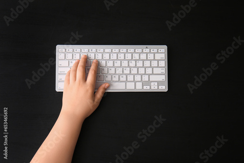 Female hand with modern computer keyboard on dark background