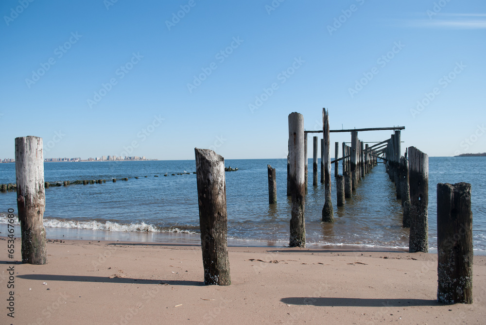 Horizon view of the ocean with wooden groynes in the water and sand. Clear blue skies. Horizon view of the ocean with wooden groynes in the water and sand. Clear blue skies.