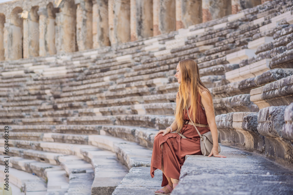 Obraz premium Woman tourist explores Aspendos Ancient City. Aspendos acropolis city ruins, cisterns, aqueducts and old temple. Aspendos Antalya Turkey. turkiye