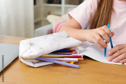 Fototapeta Naklejka Na Ścianę i Meble -  Little girl with pencil case and pair of compasses at table, closeup