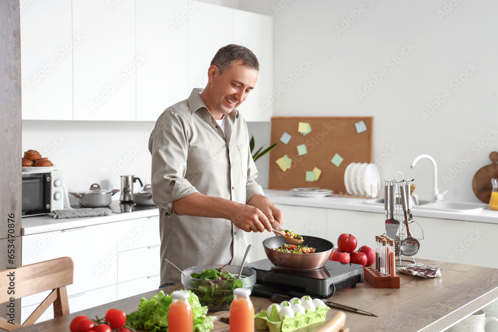Mature man frying vegetables in kitchen Mature man frying vegetables in kitchen
