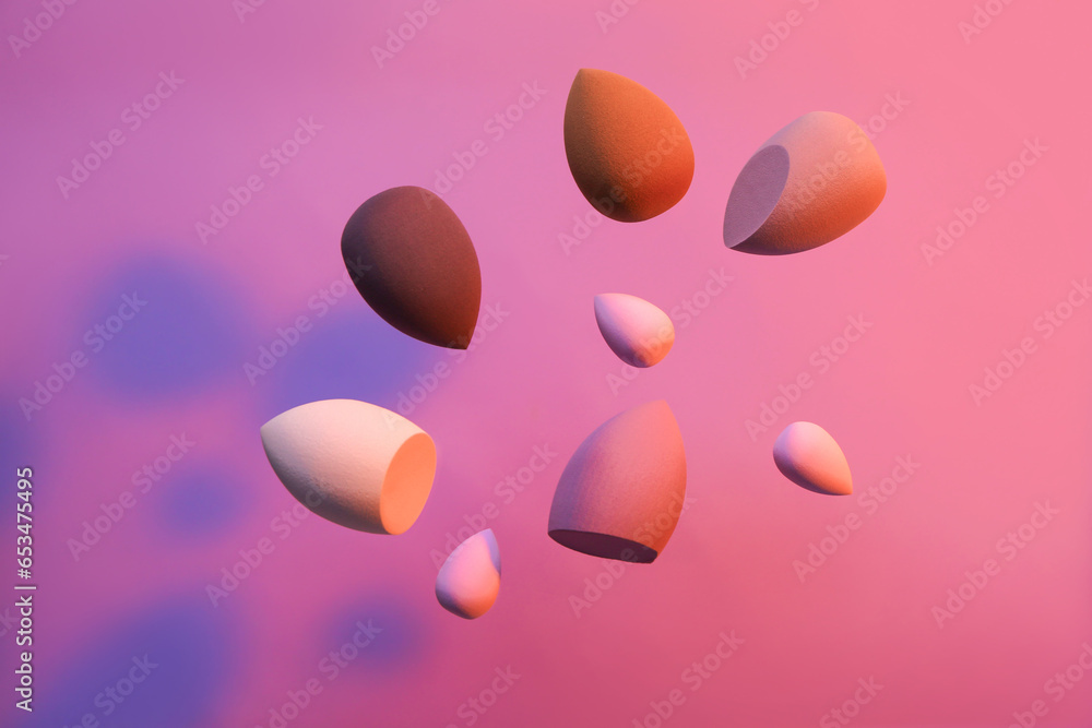 Flying different makeup sponges on purple background Flying different makeup sponges on purple background