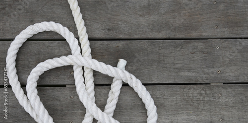 White boat rope attached to a wooden dock with dark water below
