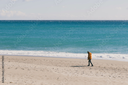 Man alone in the middle of the beach with rough sea  photo