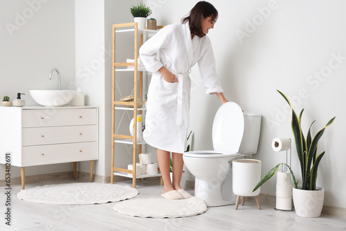 Young woman flushing toilet...
