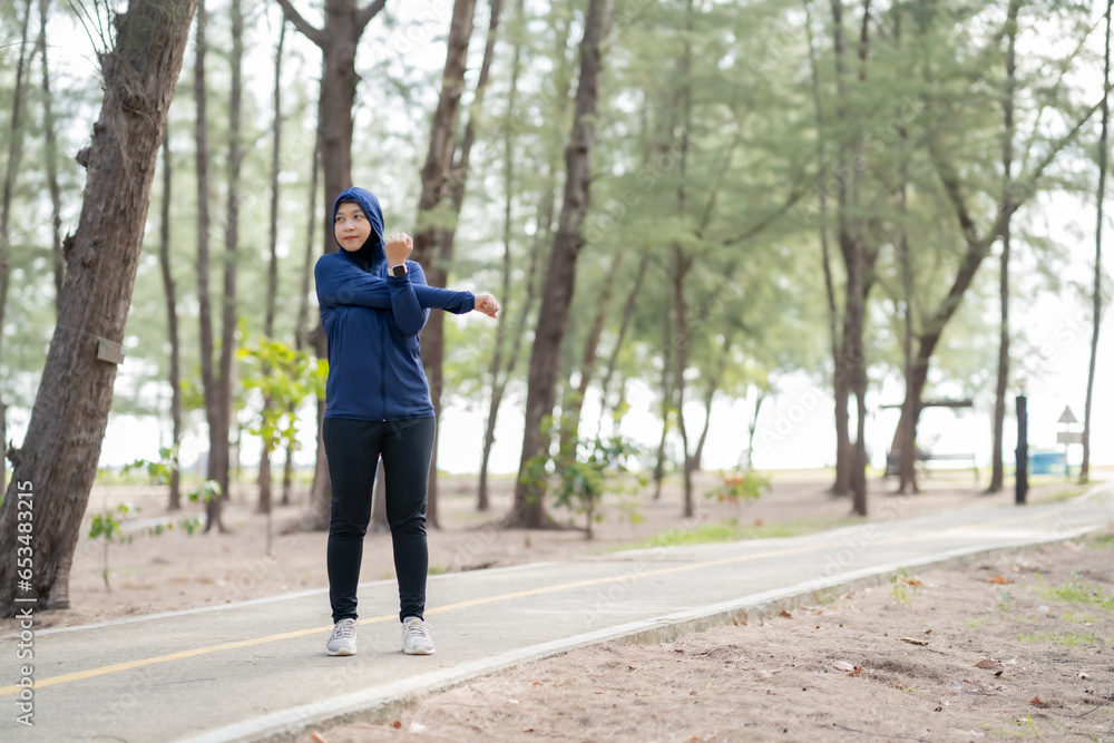Happy cheerful Middle-aged Asian Muslim woman practicing exercise and stretching and enjoy jogging at the park close up with copy space. Modern muslim woman lifestyles and diversity concept.