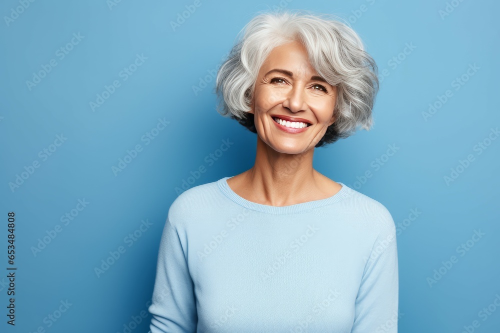 Happy senior woman. Portrait of beautiful senior woman looking at camera and smiling while standing against blue background Happy senior woman. Portrait of beautiful senior woman looking at camera and smiling while standing against blue background