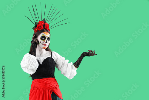 Beautiful woman dressed for Halloween showing something on green background