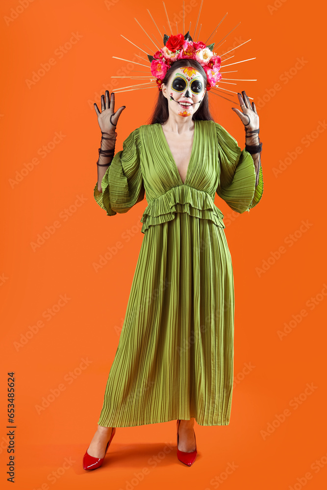 Fototapeta premium Beautiful woman dressed for Halloween on orange background