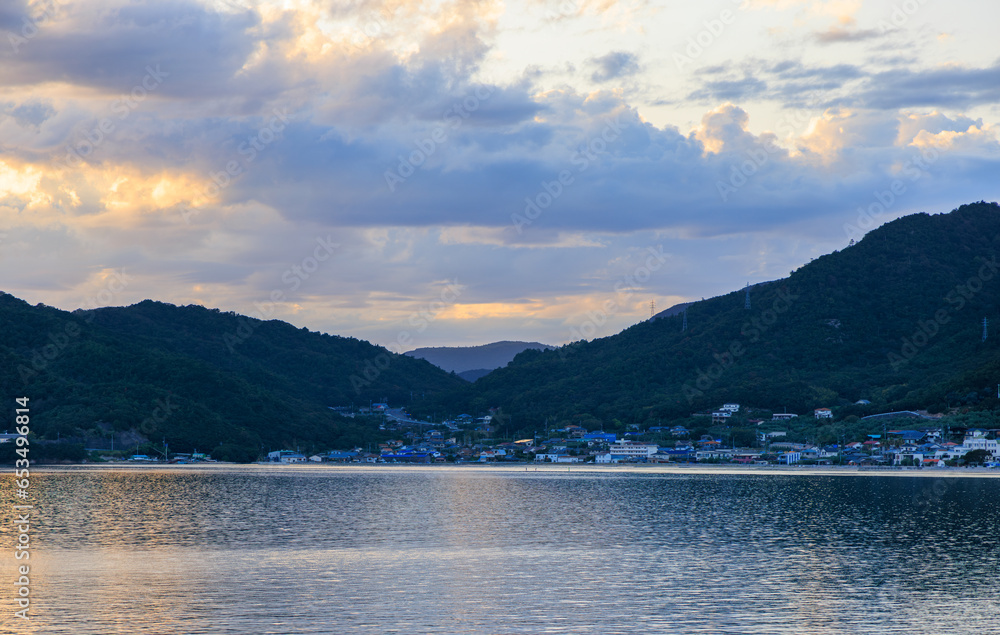 Coastal village by calm water and mountains on Shodo Island at sunset