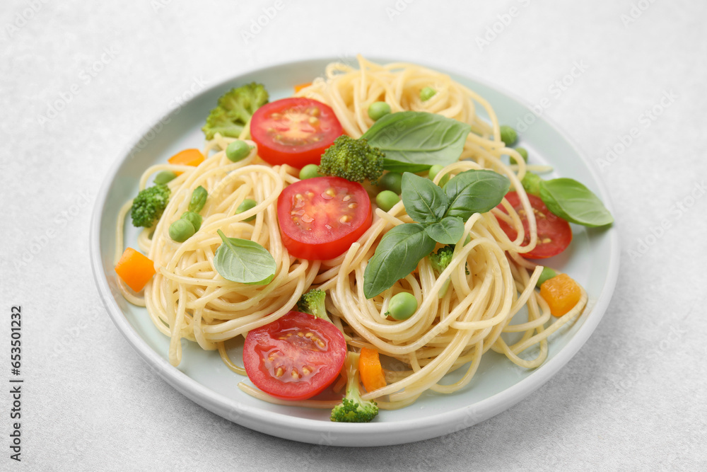 Plate of delicious pasta primavera on light gray table, closeup