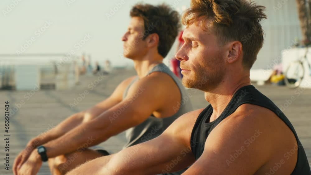 Calm people meditate on seashore during group yoga class