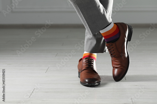Man wearing stylish shoes and colorful socks indoors, closeup. Space for text