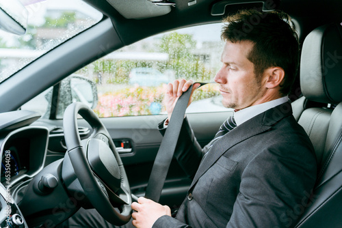 車でシートベルトをしめる外国人ビジネスマン・ドライバー・運転手・出張・外出・カーシェアリング  © buritora