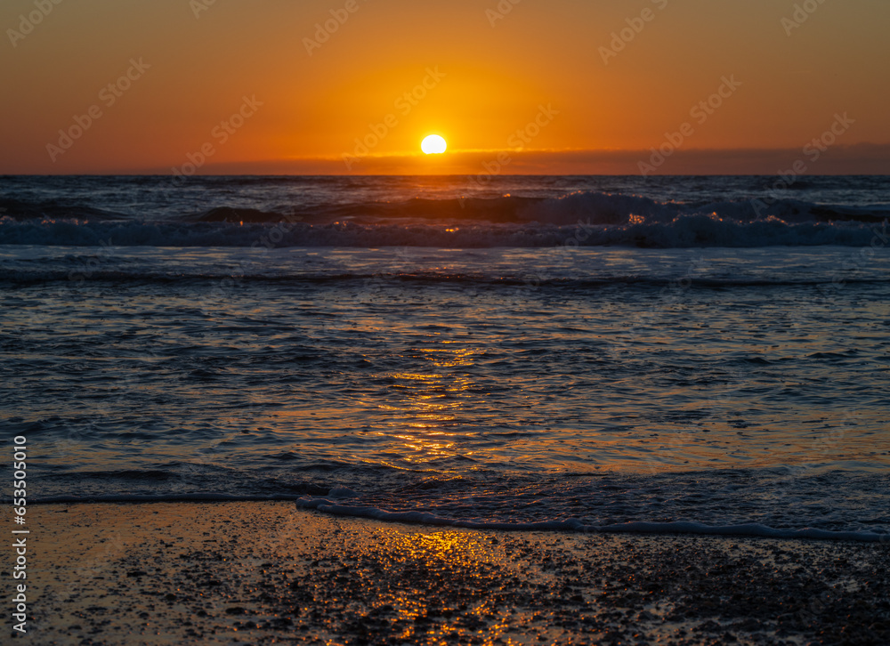 Sun rising above horizon at beach