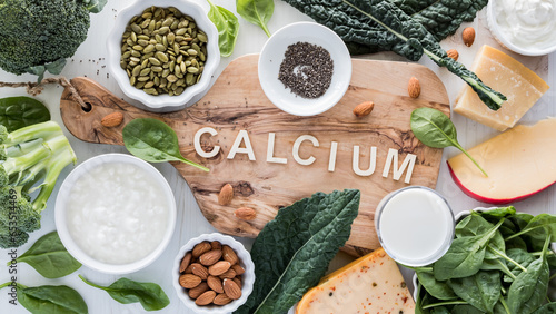 An assortment of calcium rich foods surrounding a wooden board. photo