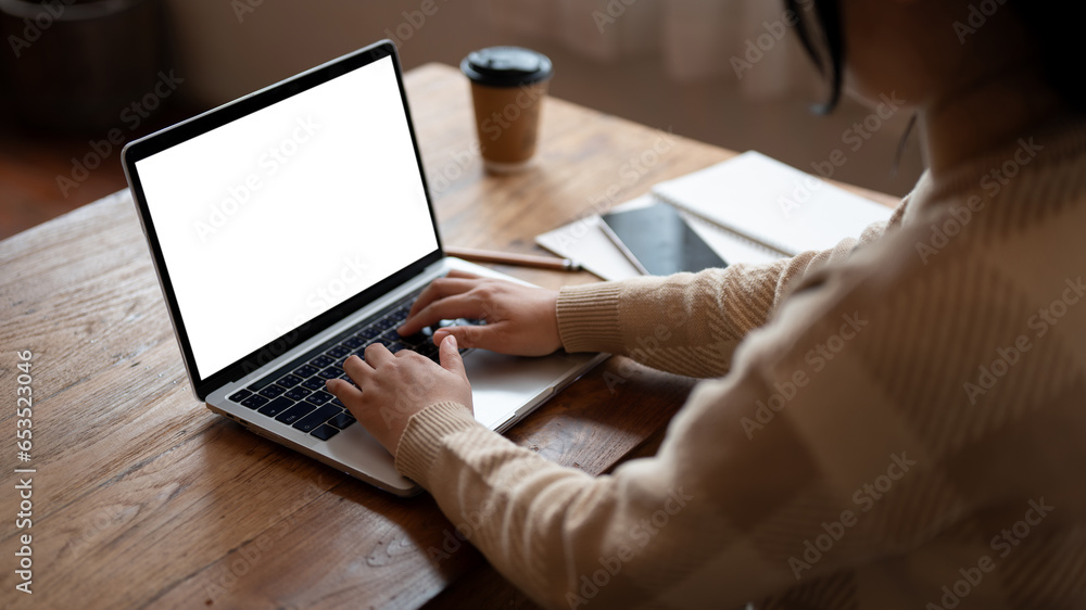 Fototapeta premium A female freelancer or college student using her laptop, working remotely at a coffee shop.