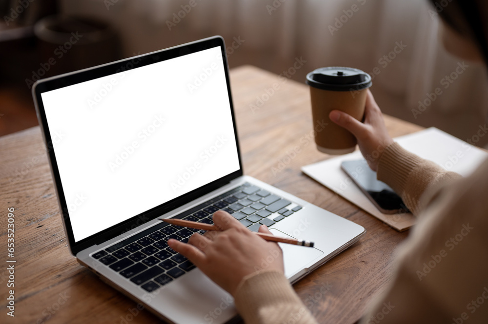 Close-up image of a woman working on her laptop while having morning coffee in a coffee shop. Close-up image of a woman working on her laptop while having morning coffee in a coffee shop.
