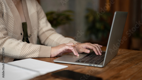 A woman working remotely at a coffee shop, working on her laptop, typing on keyboard.