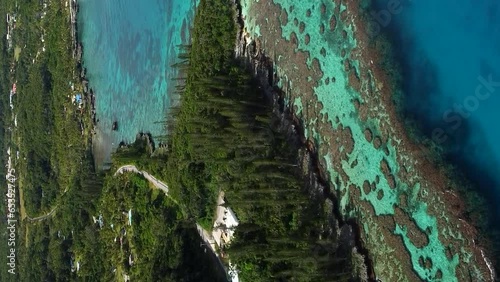 Aerial ascending shot revealing amazing coral bay beach and Tadine wharf, on Maré Island, New Caledonia. vertical format photo