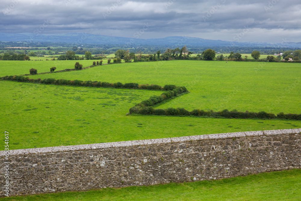 Obraz premium Lush, green countryside adjacent to Rock of Cashel at Cashel, County Tipperary, Ireland 