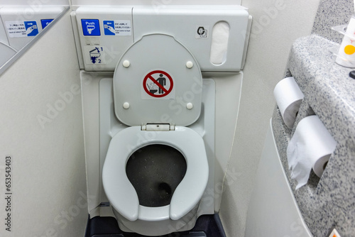 Fototapeta The toilet seat with the lid open at a aircraft lavatory