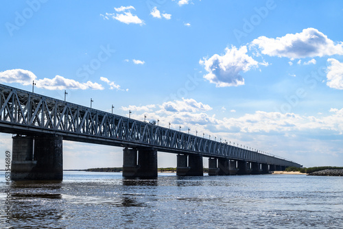 A motorway and railway bridge across the river. Blue calm river water and blue cloudy sky