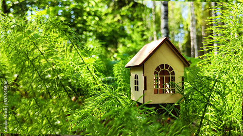 miniature toy house in forest close up, spring natural background. symbol of family. mortgage, construction, rental, property concept. Eco Friendly home. template for design. soft selective focus