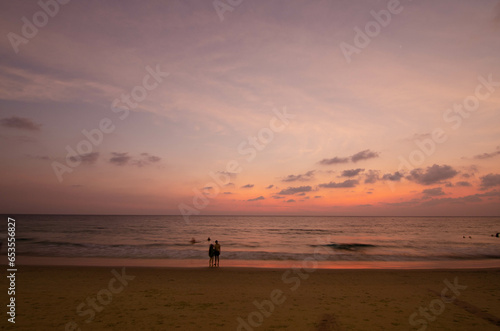 Sunset view of summer beach tropical seashore scenic white sand of Karon beach in phuket thailand with people relaxing doing activity on beach