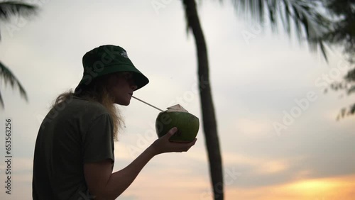 Women enjoying a fresh coconut at a beach under some palm trees, low angle shot photo