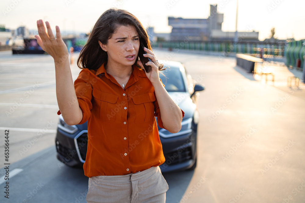 Nervous young woman standing by open car hood and calling to auto service, got broken at highway on a way to countryside. Female drive having phone conversation with friends, asking for help with auto Nervous young woman standing by open car hood and calling to auto service, got broken at highway on a way to countryside. Female drive having phone conversation with friends, asking for help with auto