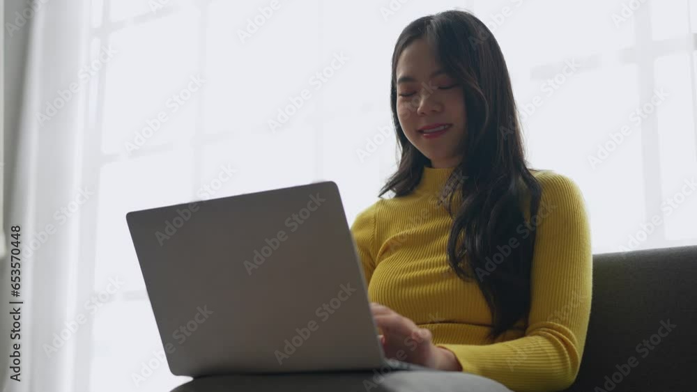 modern work lifestyle Asian businesswoman sitting the sofa at home working on laptop online using the internet holding paper documents view receiving contact information orders ship online happily. modern work lifestyle Asian businesswoman sitting the sofa at home working on laptop online using the internet holding paper documents view receiving contact information orders ship online happily.